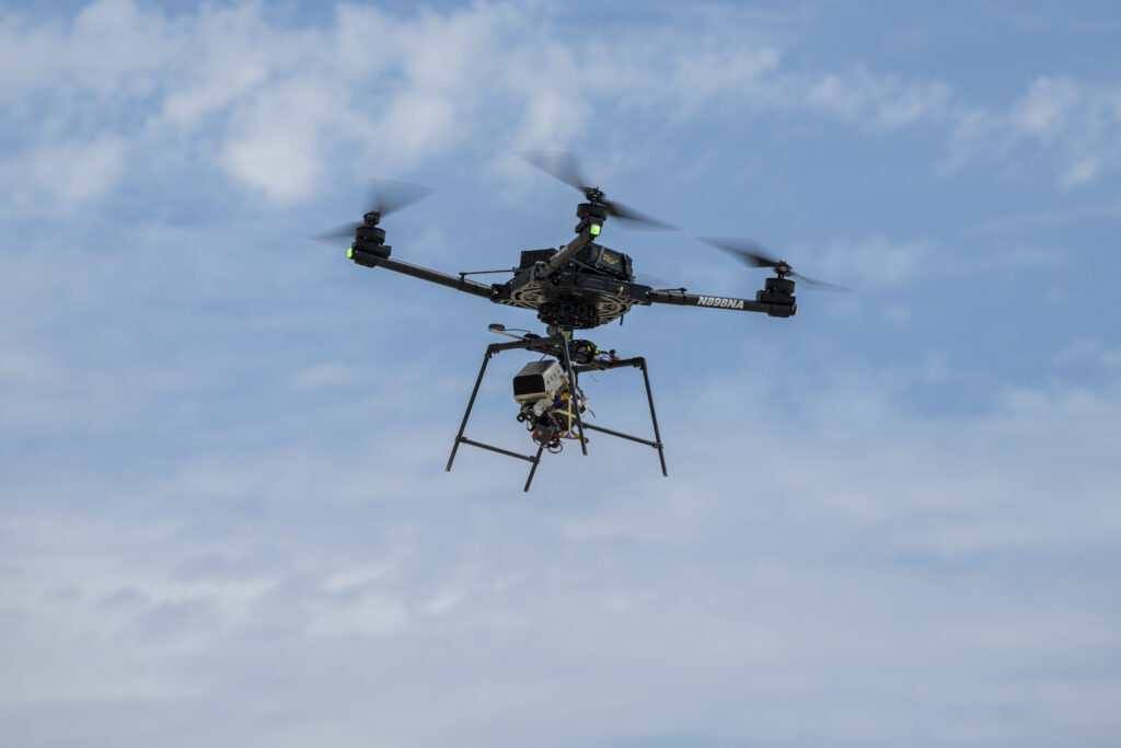 A remotely piloted drone with four rotors carries a guidance and navigation experiment through flight maneuvers.
